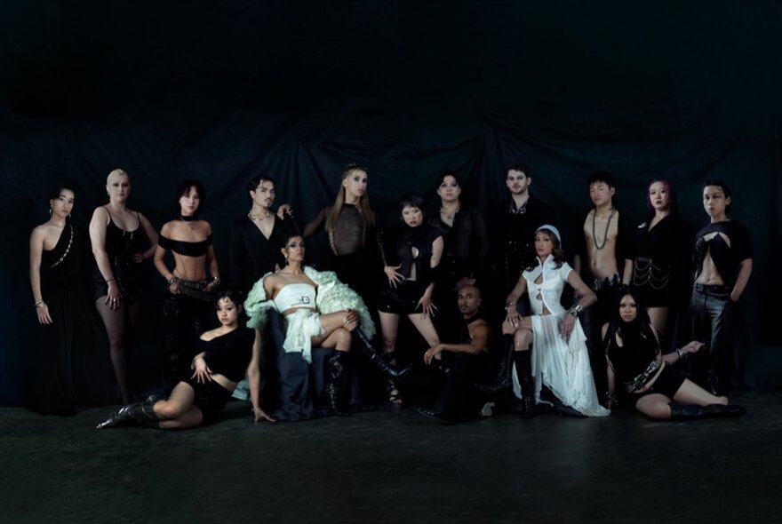 Large group of people dressed in black and white against a black background.