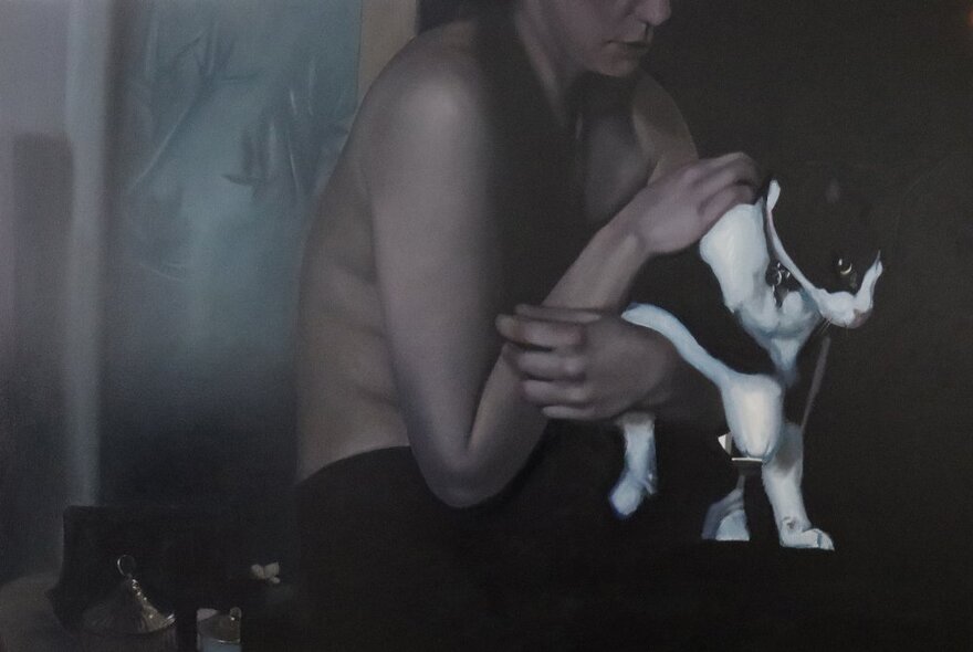 A crop of a person with a naked torso holding a black and white cat that wants to get away.