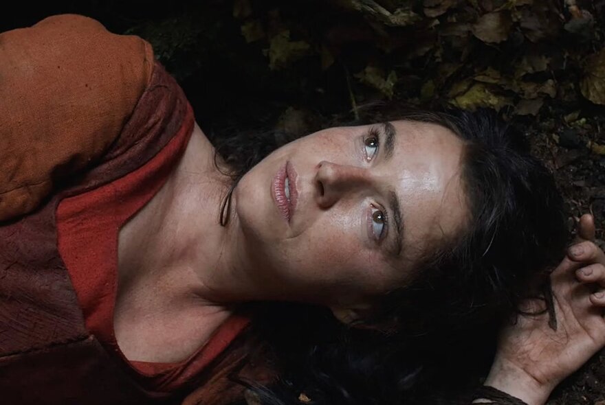 Still from the film Hamnet, with actress Jessie Buckley lying on the ground looking up.