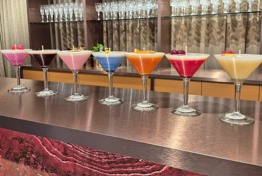 A line of martini glasses turned into colourful cocktail-inspired candles.