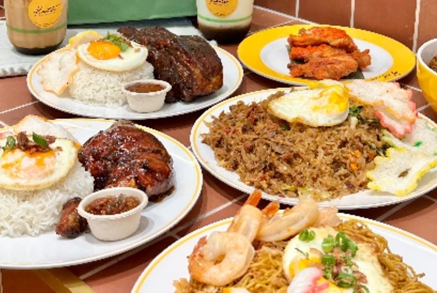 A table set with multiple Indonesian dishes, some with small tubs of condiments on the site and all of them with a fried egg on top. 