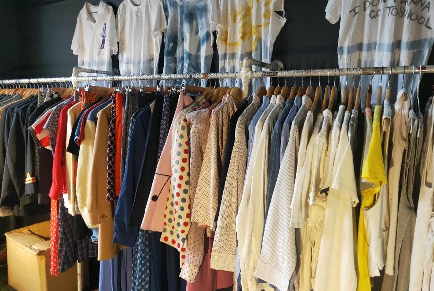 Vintage and antique clothing hanging neatly from a rack inside a small retail space. 