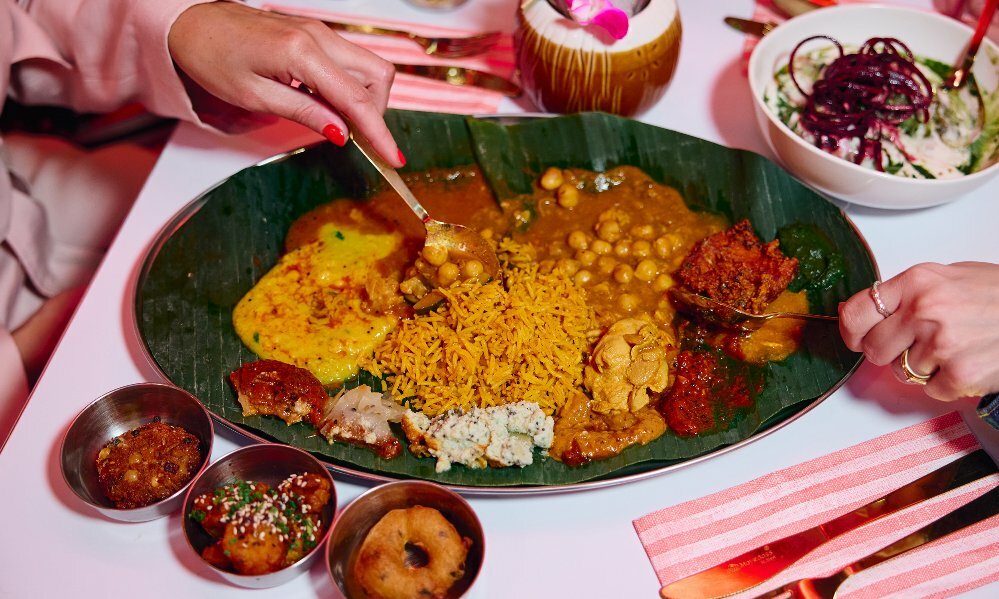 A selection of Indian curries and rice on a banana leaf.