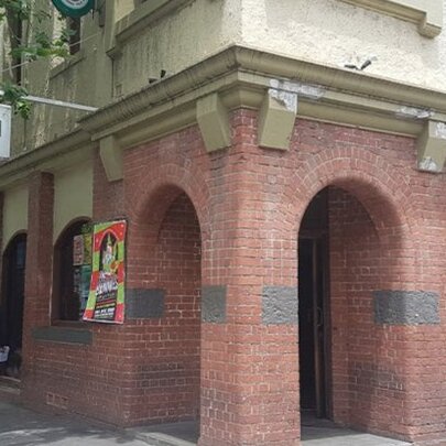 Man wearing a hat walking past the Curtin Hotel exterior with arched brick entry.