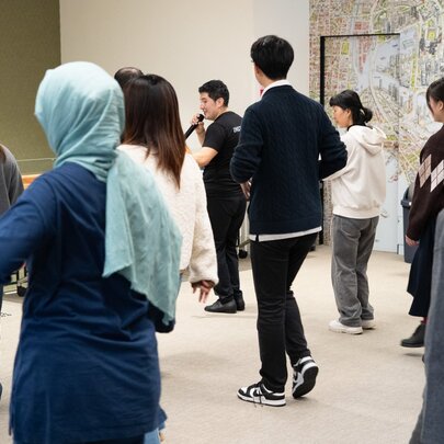 An interactive dance workshop in a studio, where participants are learning a dance following instructions from a man holding a microphone.