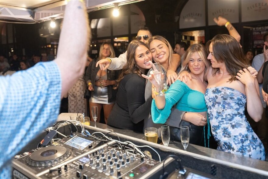 People crowded around a DJ booth glasses of wine.