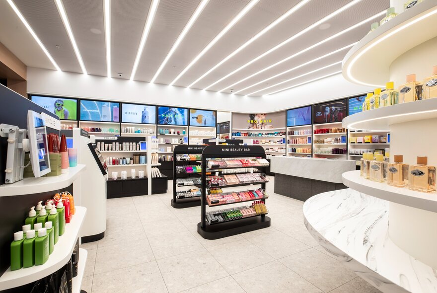 A brightly lit interior of a beauty store with multiple white and black cosmetic display stands and shelves lined with beauty products.