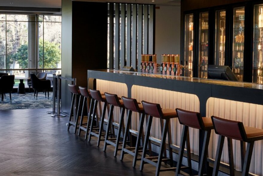 Interior of Cliveden restaurant with high stools linked up against the bar, and views out large windows onto Fitzroy Gardens.