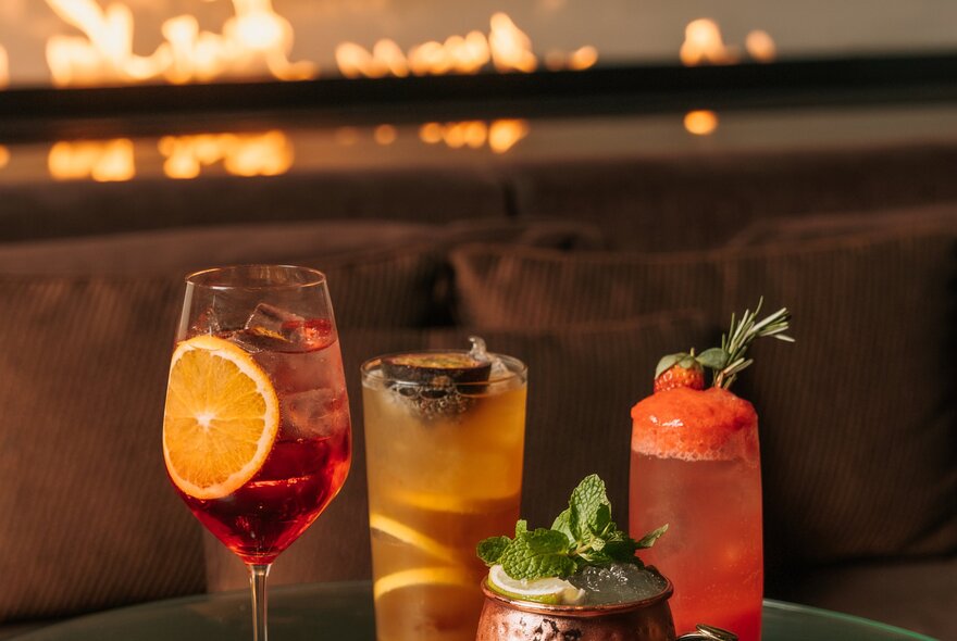 A selection of different cocktails in a bar with glowing lights in the background.