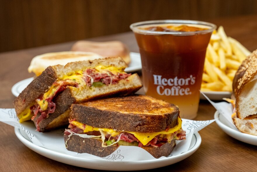 A plate with a toastie on it and a coffee in the background.