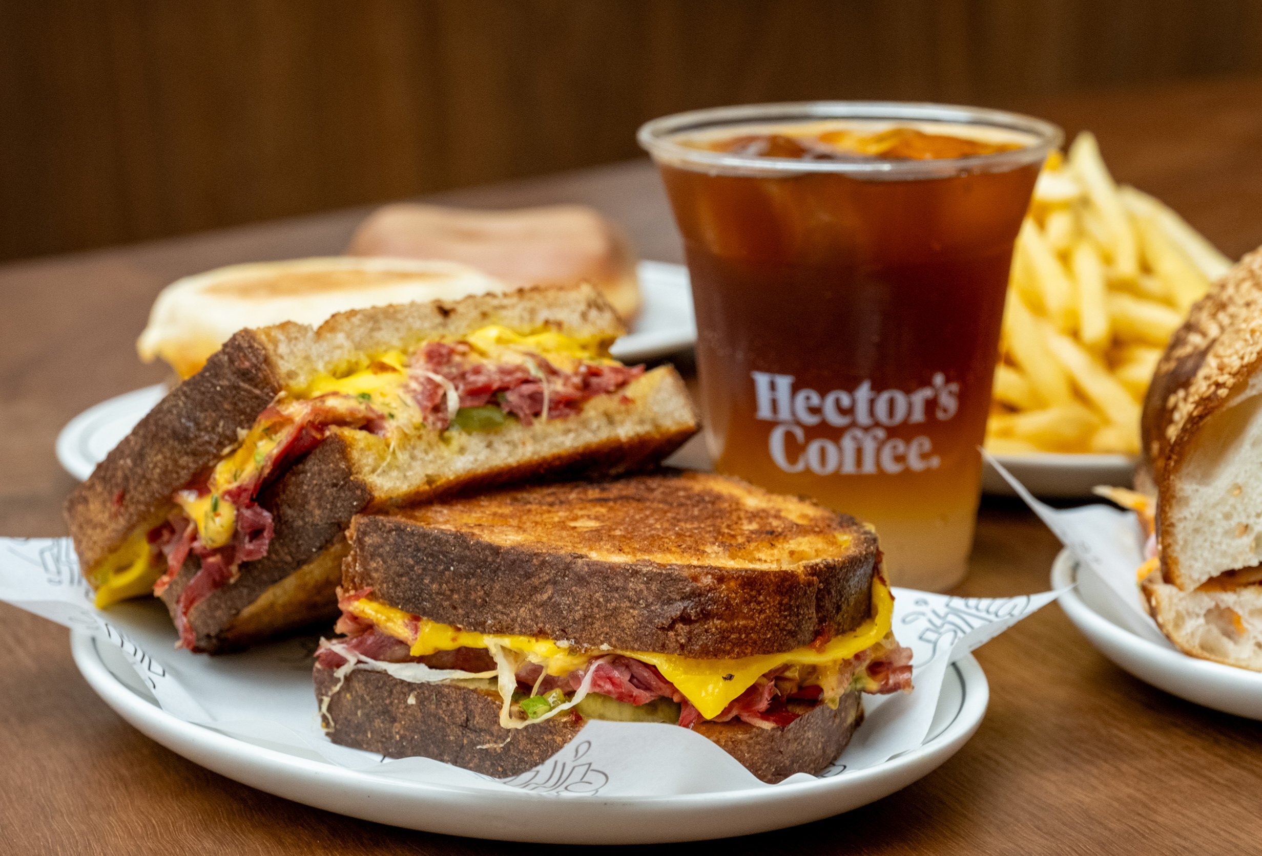 A plate with a toastie on it and a coffee in the background.