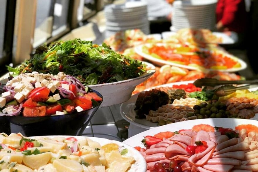 Bowls of salad and platters of meat and seafood on a table.