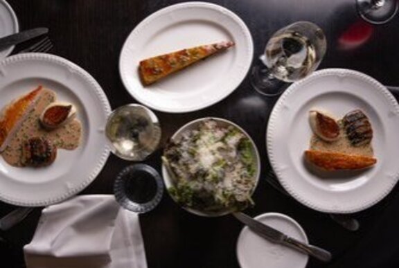 A selection of gourmet dishes arranged on a dark surface, seen from above.
