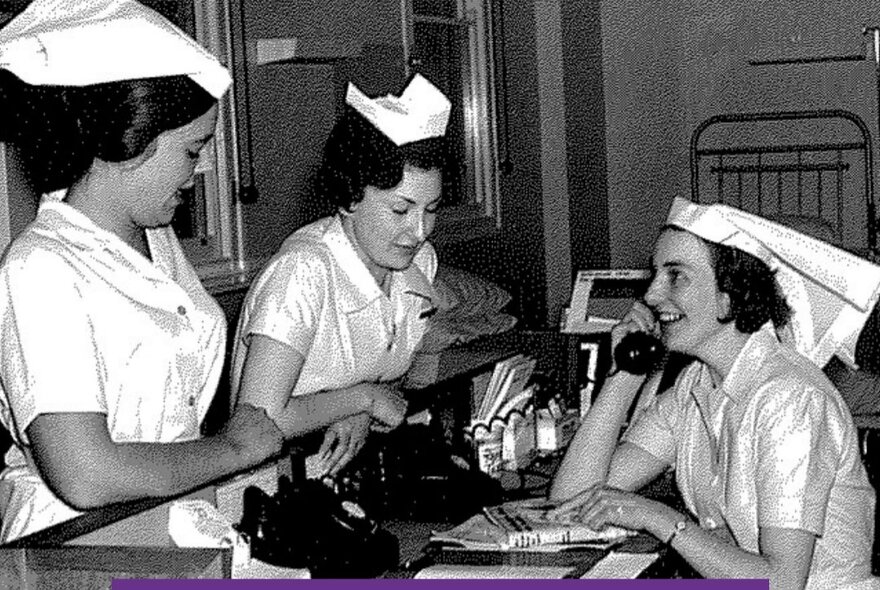 Mid-century image of nurses at a hospital desk, one on a telephone.