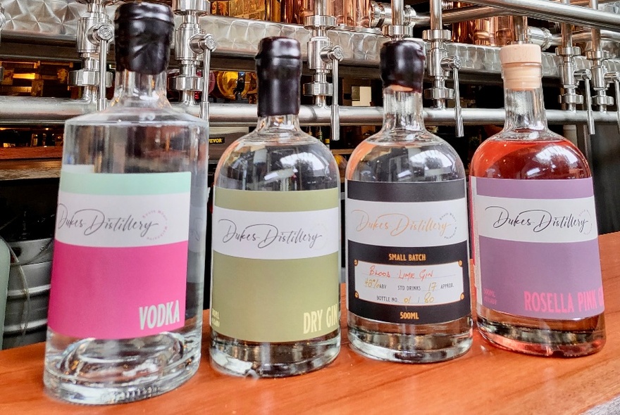 A row of Dukes Distillery bottles lined up on a counter.