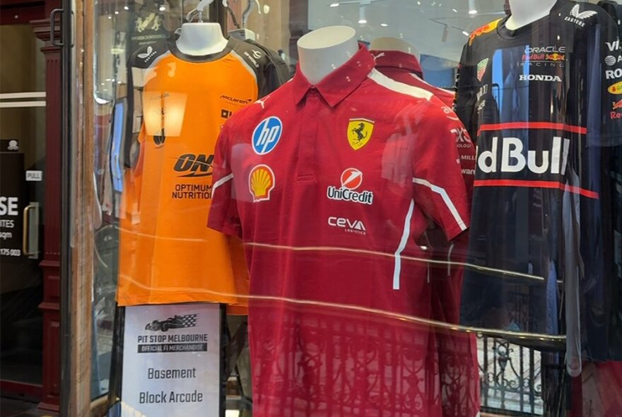 Shop window with mannequins wearing F1 team jerseys.
