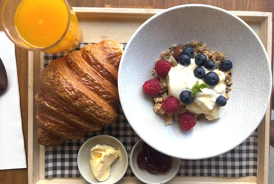 Breakfast tray with orange juice, croissant and muesli.