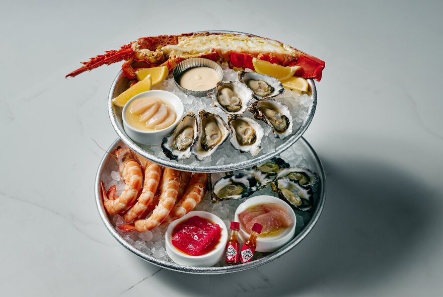 Two-tiered seafood platter with oysters, lobster, scallops, prawns and muscles.