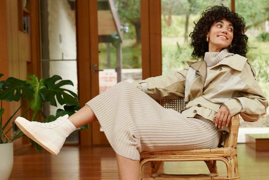 A woman leaning back in her chair wearing white high top sneakers.