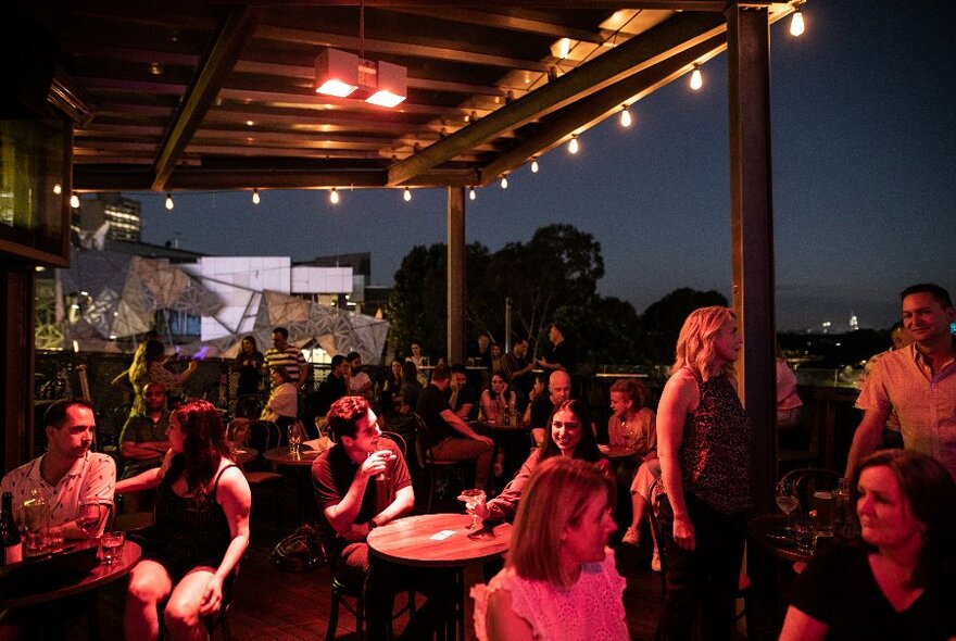 Diners at a rooftop bar at night.