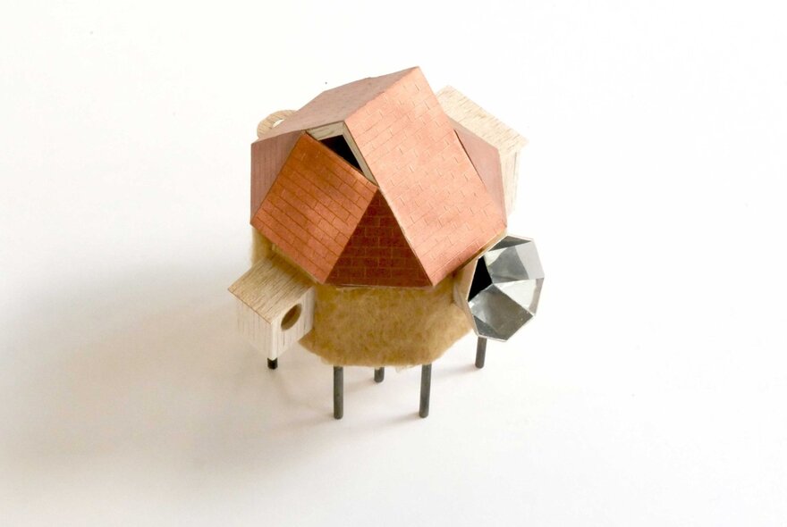 A small hand crafted object resembling a structure, on raised legs, with a roof and adornments, against a white background.