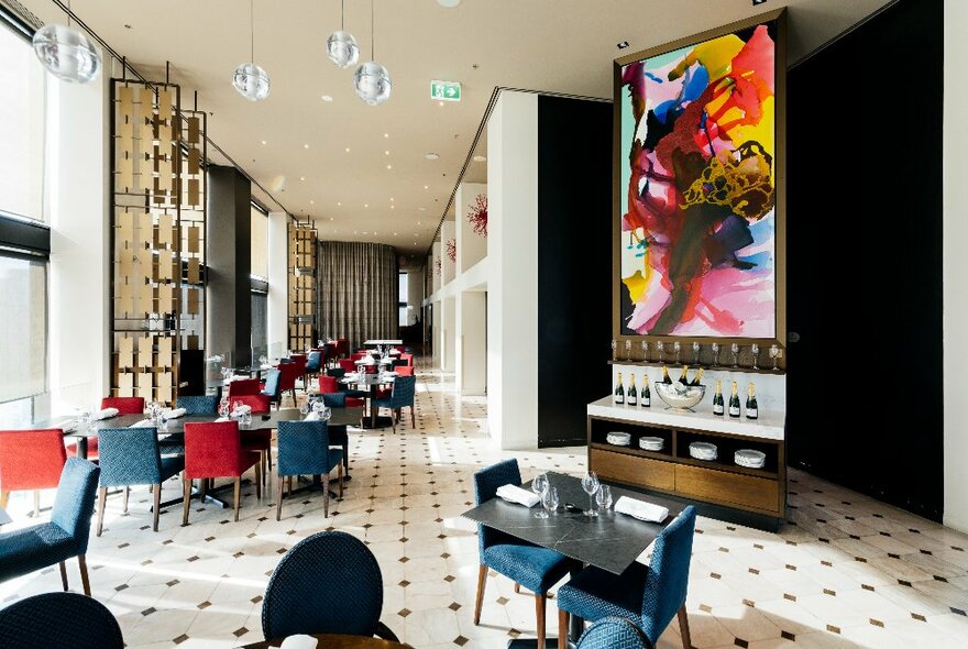 A spacious restaurant at Sofitel on Collins, with chairs arranged around tables and a black and white patterned floor.