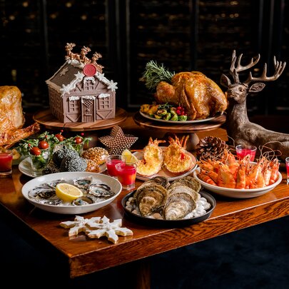 A Christmas buffet including seafood, ham and turkey plus a gingerbread house and a statue of a reindeer.