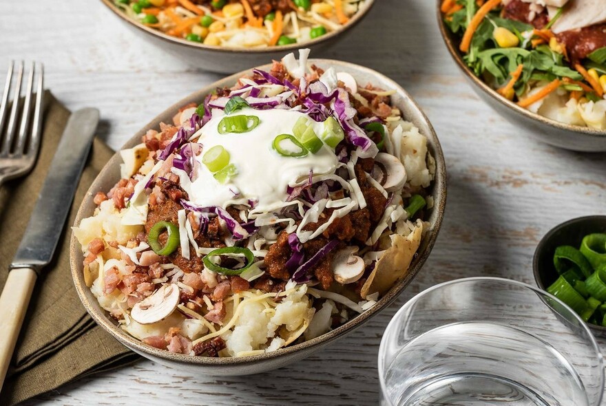 Table setting with potato dishes, including sour cream and coleslaw.