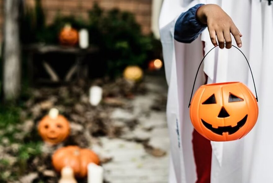 White-robed figure holding a pumpkin lantern.
