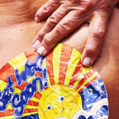 Person holding an old sticker to the base of their spine.