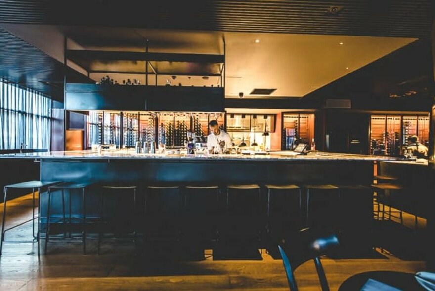 Bartender preparing drinks behind a bar area.