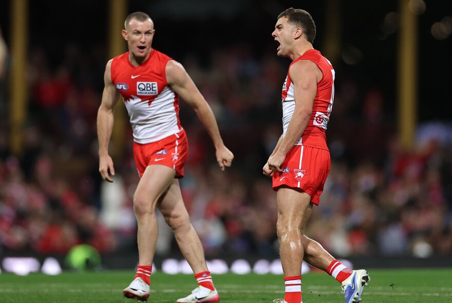 Two Sydney Swans players talking on the footy field. 