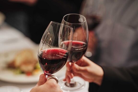 Two glasses of red wine being held together in a cheers celebration.
