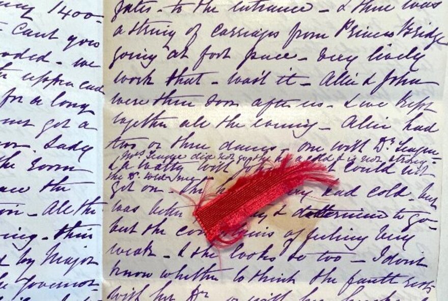 Historic letter written in purple cursive ink, with a red piece of red silk.