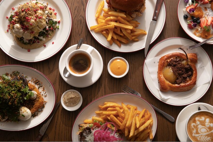 Overhead view of plates of food on a table, cutlery and a cup of coffee.