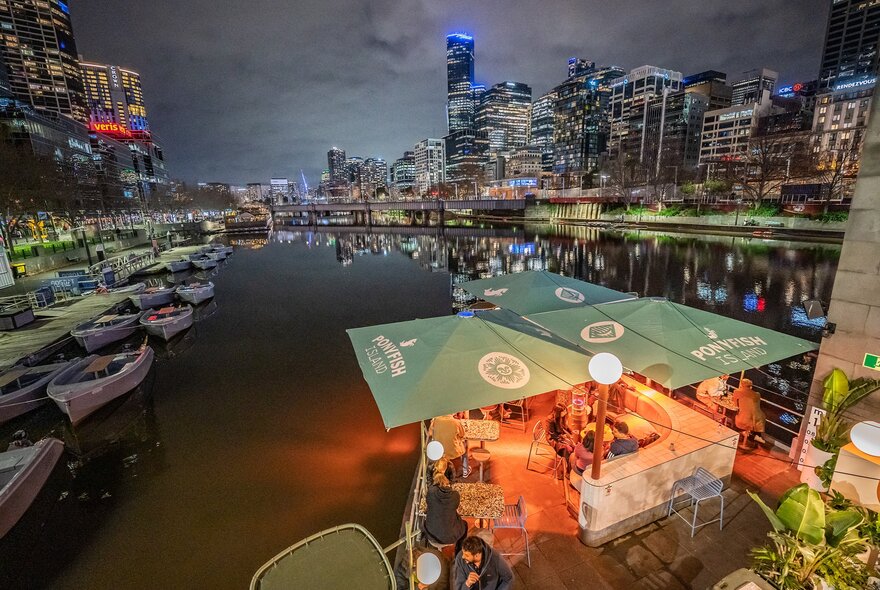 A bar on a river at night with Melbourne's city skyline in the background.
