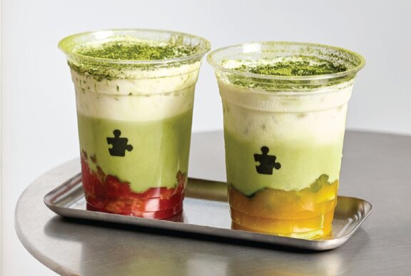 Strawberry and mango flavoured matcha drinks in plastic cups on a silver tray