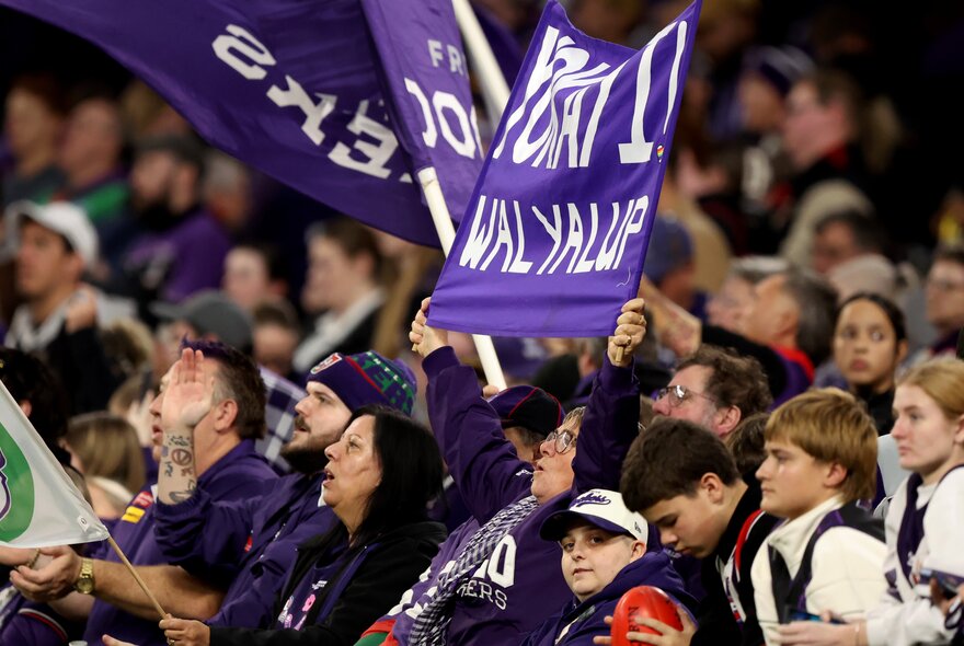 Football fans in a sports ground waving the team's colours and flags.