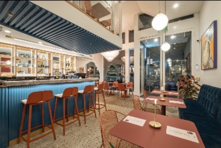 Interior or Mr Hugo cafe with high stools at the bar, banquette seating along one wall with tables and chairs.