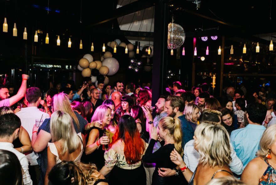 A crowd of people dancing and celebrating on the dancefloor at General Assembly bar.