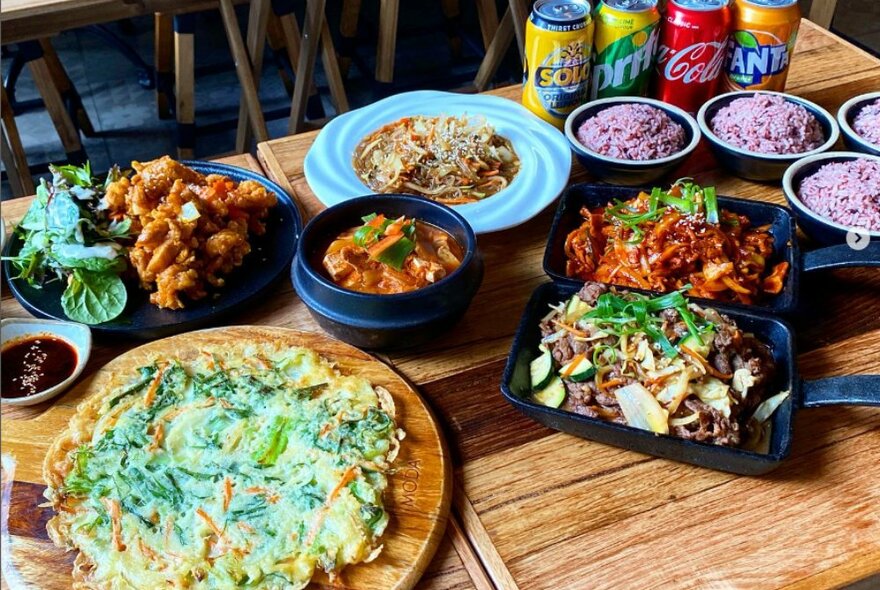 Table full of food, spicy fried chicken, rice, stew, egg omelette and more.