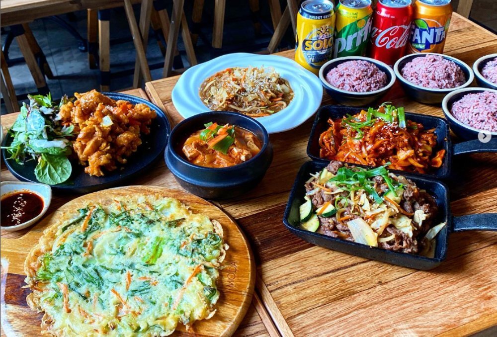 Table full of food, spicy fried chicken, rice, stew, egg omelette and more.
