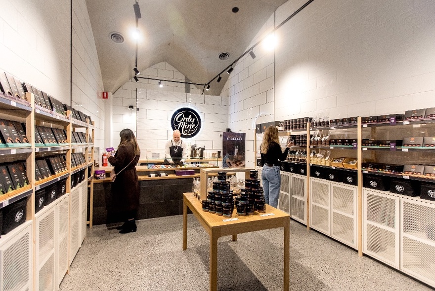 People browsing in a shop with a stark interior and table in the middle and shelves lined with black products