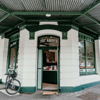 The corner site of Melbourne sandwich shop, Fat Andy's, with cream brickwork and dark green accents and a bicycle parked out the front.