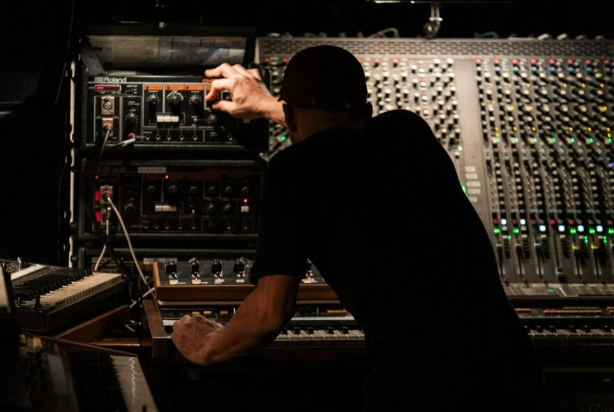 German composer and musician, Nils Frahm, pressing a button on a sound mixer.