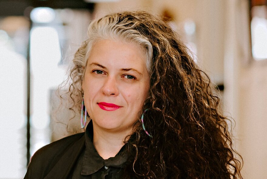 Woman with long grey and brown, wavy hair.