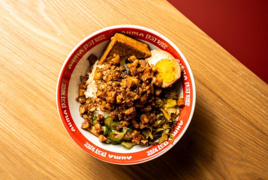 Looking down onto a timber table with a bowl of Taiwanese pork rice. 