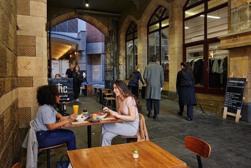 Two friends are eating brunch inside a cafe which is located in a church laneway