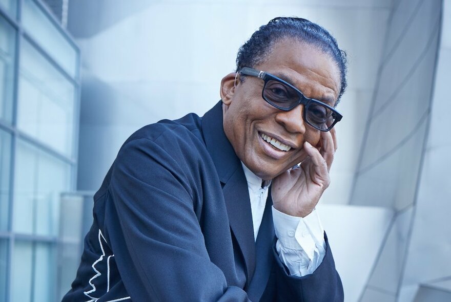 Jazz musician Herbie Hancock, holding his face to his hand and wearing sunglasses.