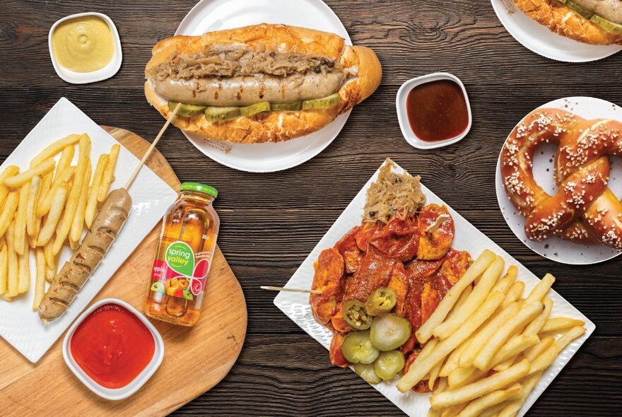 Looking down at a table set with German dishes like bratwurst and pretzels.